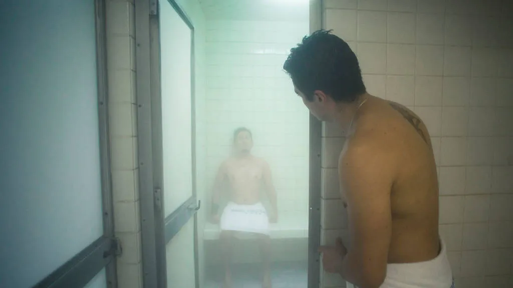 gay male sitting in gay mexico city bathhouse banos rocio while hot naked male gay cruises in the doorway via time out magazine photograph by Alejandra Carbajal
