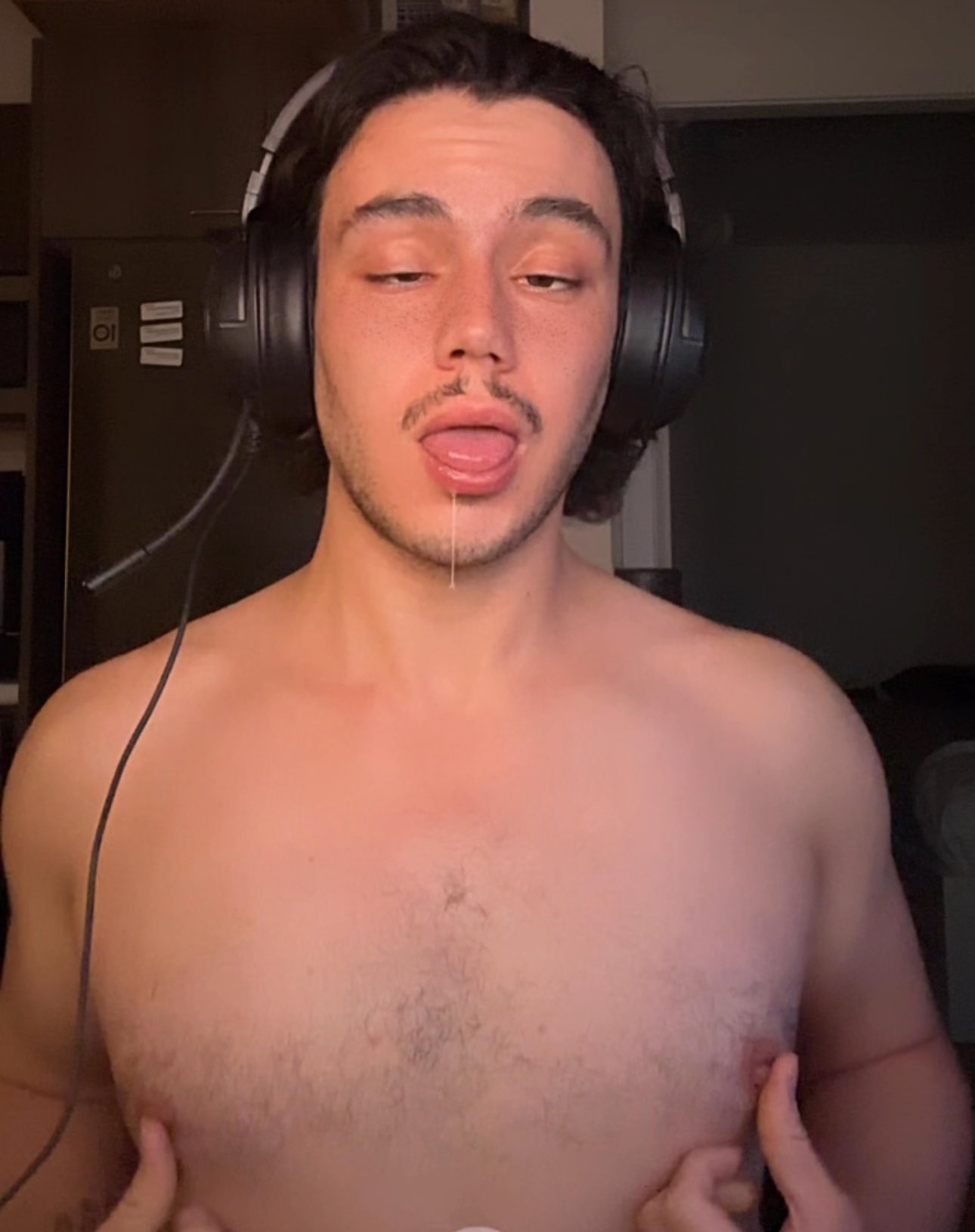 gay male onlyfans perfomer Pup_leviXXX playing with his nipples and masturbating and gooning with his headphones on with his tongue sticking out