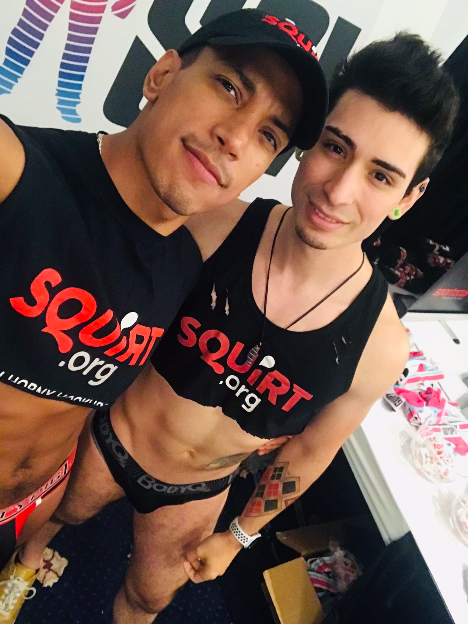 gay xxxx onlyfans content creator working Folsom Fair wearing Squirt.org crop tops and underwear smiling for a phone selfie