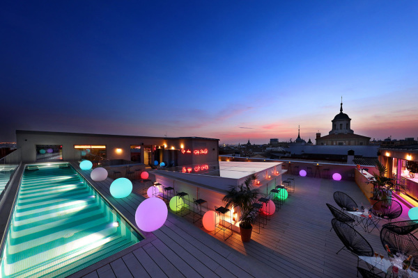 the Sky Bar rooftop in Axel Hotel Madrid at nighttime with sunset sky and colorful lights via Axel Hotel Madrid