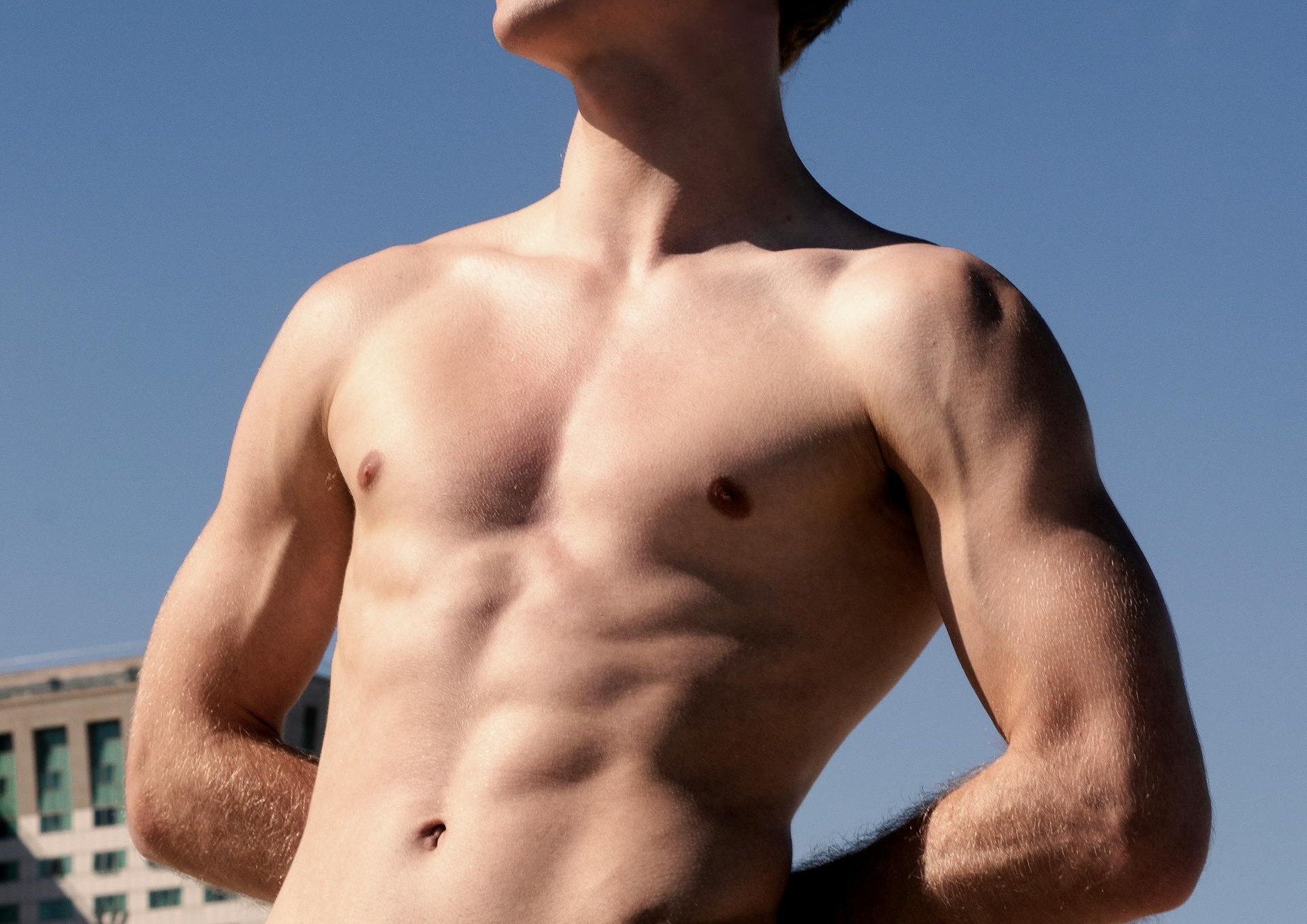 gay shirtless male twink outside posing and showing off his tight muscle body ready for gay hookups