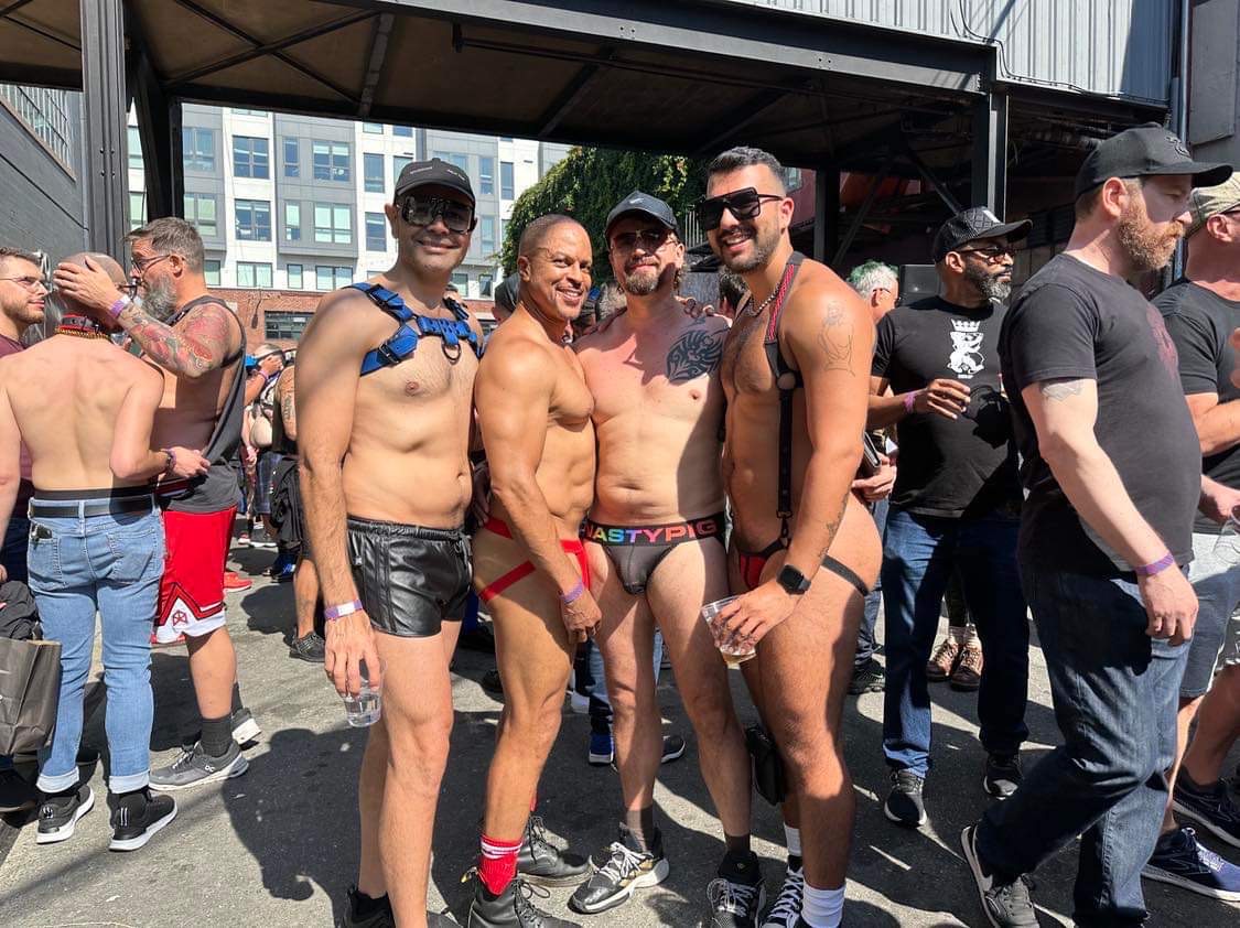 Four gay males half naked wearing jockstraps outside in the middle of Folsom Street Fair 2023 in San Francisco