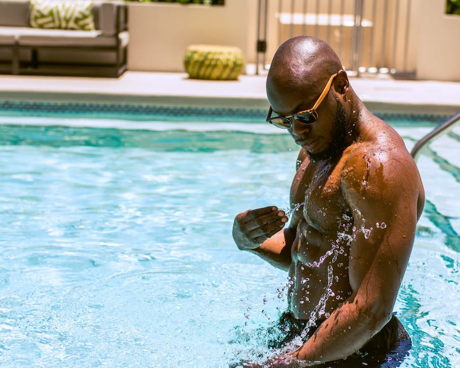 gay black male wearing sunglasses in the pool splashing water ready and cruising for hot gay sex