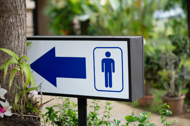 bathroom sign with male symbol and blue arrow pointing patrons to local public bathroom in local gay cruising park near you via AdobeStock
