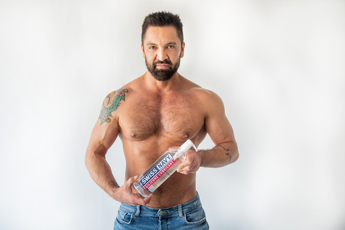 Swiss Navy Pride Brand Ambassador Dominic Pacifico holds giant bottle of gay sex lube Swiss Navy