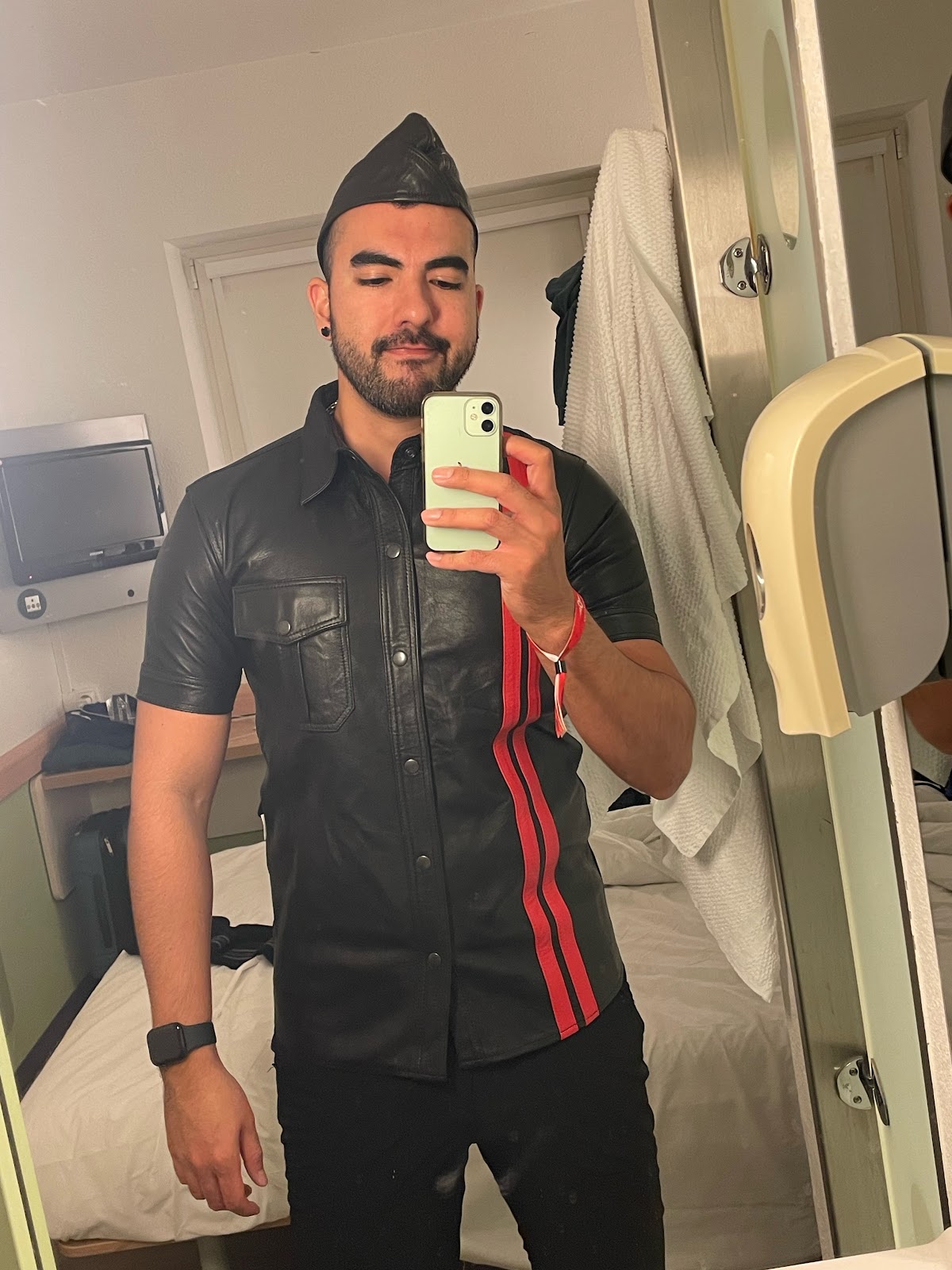 gay onlyfans content creator phil taking an iphone mirror selfie wearing red and black leather button up shirt
