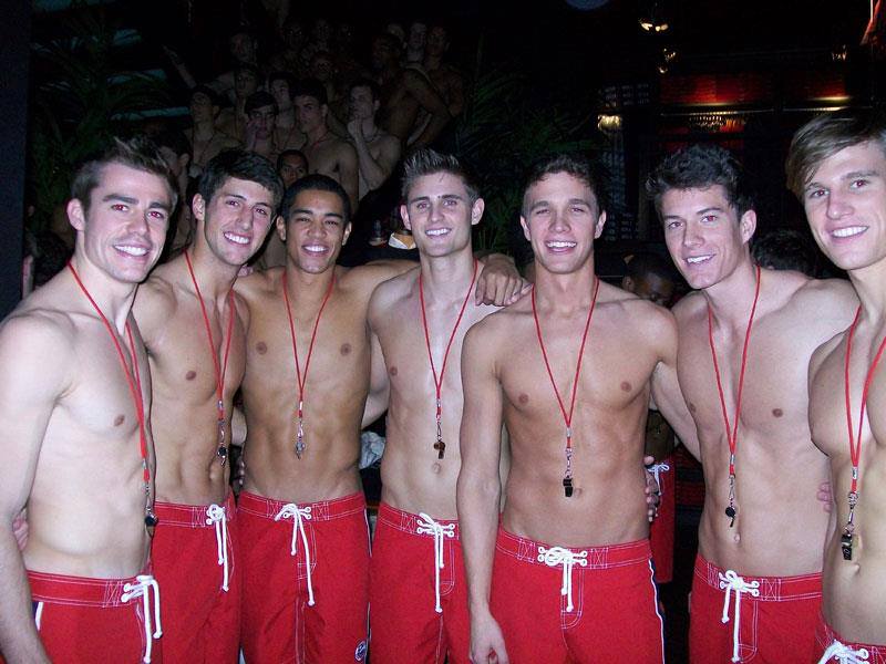 shirtless males standing in red shorts with white drawstrings pretending to be lifeguards Photo credit Robert Caplin for Hollister